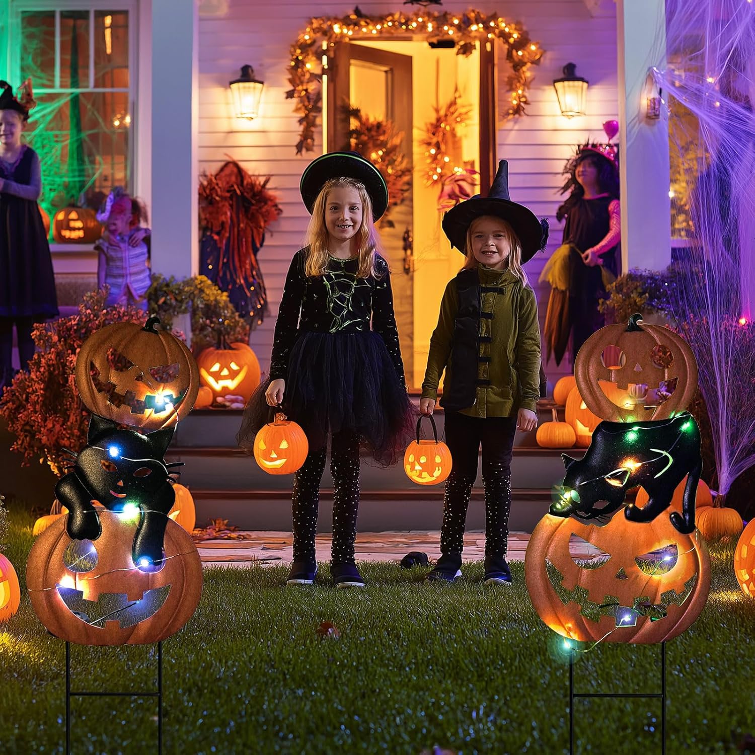 two kids in the frontyard with pumpkin and black cat garden stakes