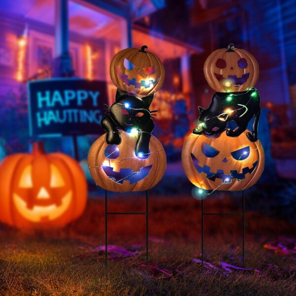 a solar led pumpkin and black cat garden stakes in the front yard