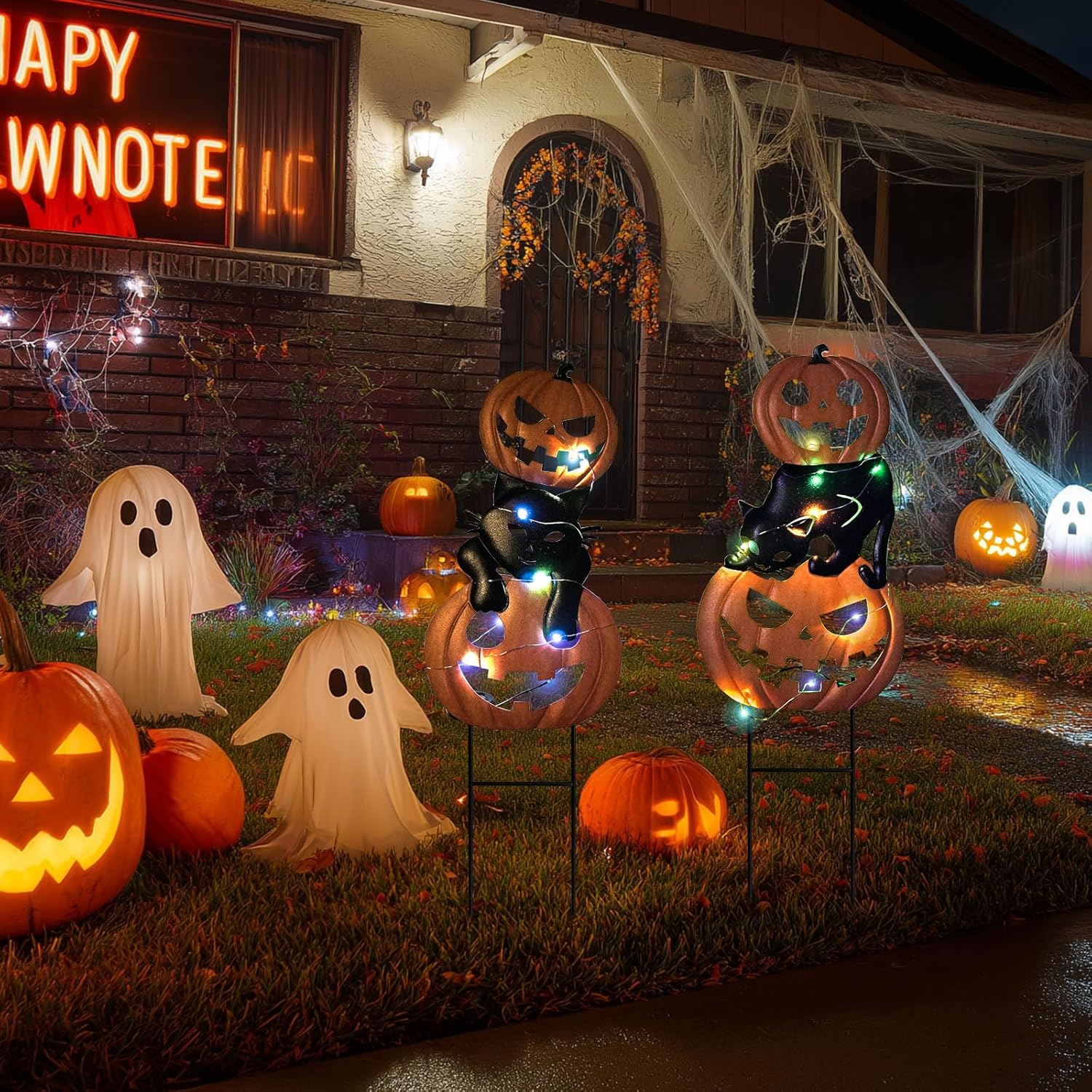 a pair of pumpkin and black cat garden stakes in a night view with LED lights